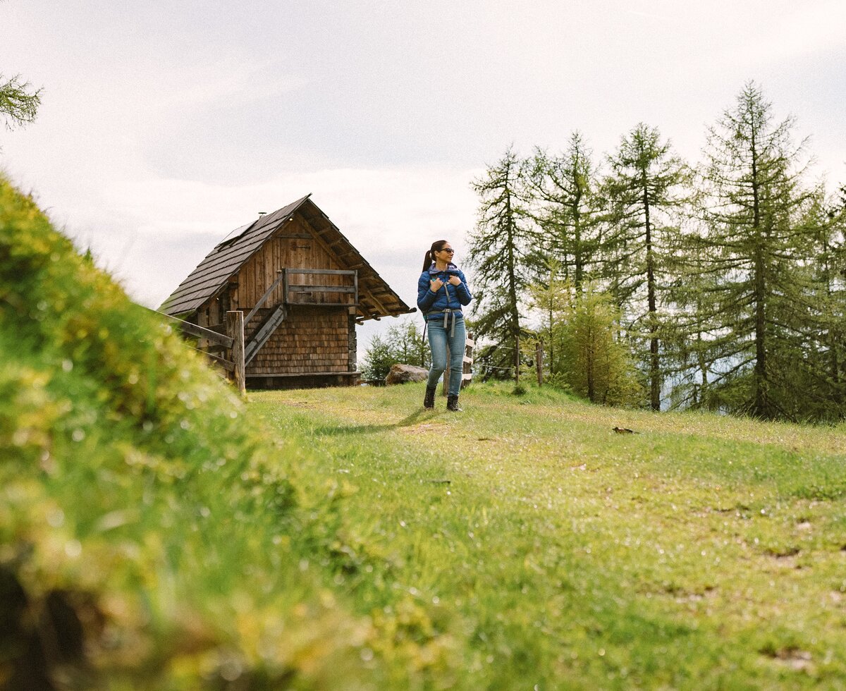 Eine Frau am Wandern | © Urlaub am Bauernhof / Daniel Gollner Eine Frau wandert von der Hütte weg. Im Hintergrund erkennt man die Rückseite der Almhütte. | © Urlaub am Bauernhof / Daniel Gollner