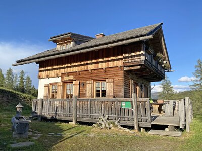 Traditionelles bayerisches Bergbauernhaus mit Holzbalkonen, Schindeldach und eingezäunter Terrasse in idyllischer Waldlandschaft. | © Urlaub am Bauernhof Kärnten / Jasmin Kreulitsch