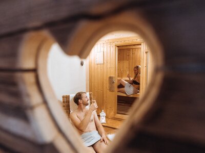 Paar in Sauna / Toms Jäger Lodge | © Urlaub am Bauernhof / Achim Mandler Couple relaxing in a rustic wooden sauna, enjoying the warmth and each other's company. | © Urlaub am Bauernhof / Achim Mandler