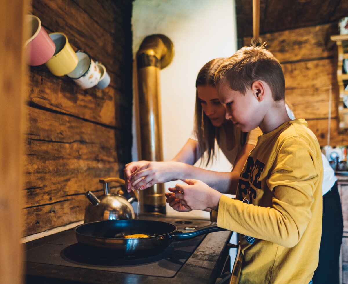 Gemeinsam Kochen auf der Almhütte | © Urlaub am Bauernhof Salzburg / Daniel Gollner Mutter mit Sohn bereiten gerade eine Eierspeise auf dem Herd vor | © Urlaub am Bauernhof Salzburg / Daniel Gollner