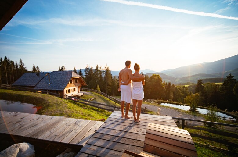 Paar steht vor der Sauna und betrachtet den Sonnenuntergang | © Urlaub am Bauernhof Steiermark / Daniel Gollner 