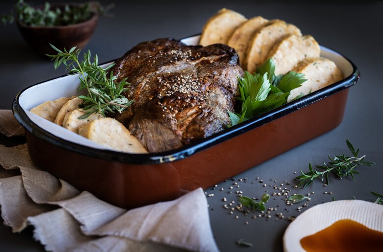 Schweinsbraten mit Semmelknödel verziert mit Kräutern in einer Auflaufform | © Florentina Klampferer/ Urlaub am Bauernhof Kärnten