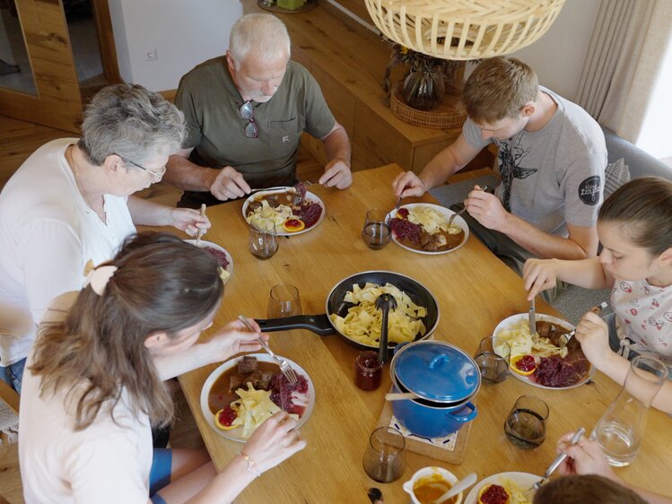 Familie Steiner sitzt gemeinsam beim Tisch und isst das Hirschgulasch | © Daniel Gollner/ Urlaub am Bauernhof Kärnten