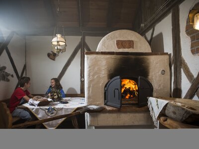 Kinder sitzen neben dem Ofen in der Stube | © Martin Steinthaler