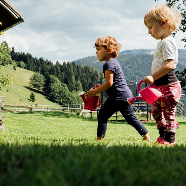 Kinder mit Gießkannen auf der Wiese | © Urlaub am Bauernhof Kärnten / Daniel Gollner