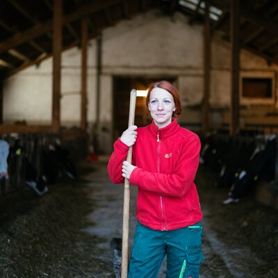 Frau steht mit Mistgabel in der Hand vor dem Stall | © Urlaub am Bauernhof Kärnten / Daniel Gollner