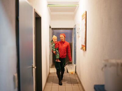 Die Kinder werden oft in den Stall mitgenommen | © Urlaub am Bauernhof Kärnten / Daniel Gollner Frau mit Kind am Arm | © Urlaub am Bauernhof Kärnten / Daniel Gollner