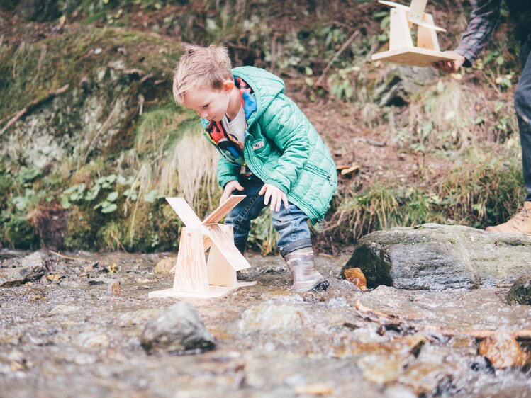 Kind mit selbstgebastelten Mühlrad im Bach | © Urlaub am Bauernhof Kärnten / Daniel Gollner