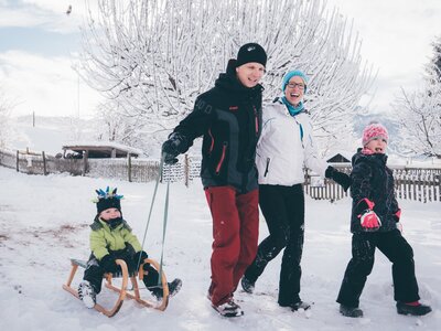 Familie geht mit dem Schlitten am Weg | © Urlaub am Bauernhof Kärnten / Daniel Gollner