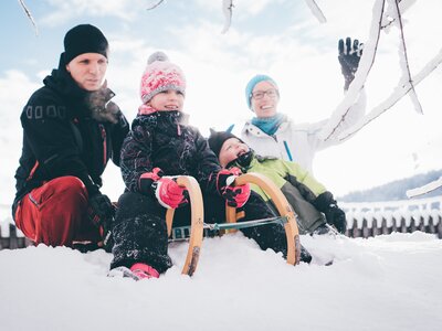 Mann und Kind beim Schlittenfahren | © Urlaub am Bauernhof Kärnten/ Daniel Gollner