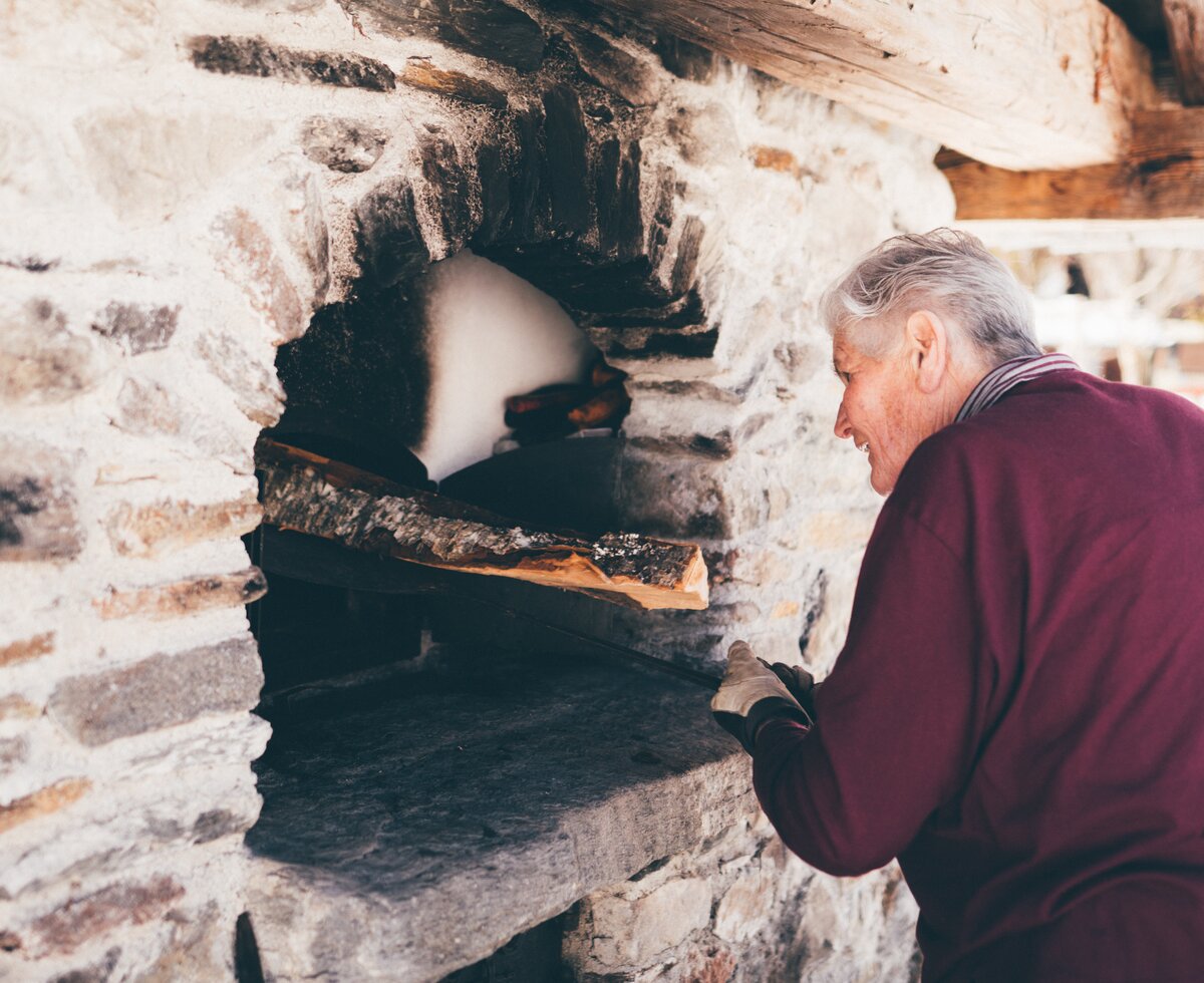 Bäuerin gibt Holz in den Ofen | © Urlaub am Bauernhof Kärnten / Daniel Gollner
