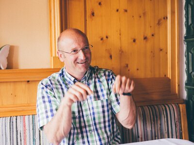 Mann sitzt bei Tisch und erklärt etwas | © Urlaub am Bauernhof Kärnten / Daniel Gollner