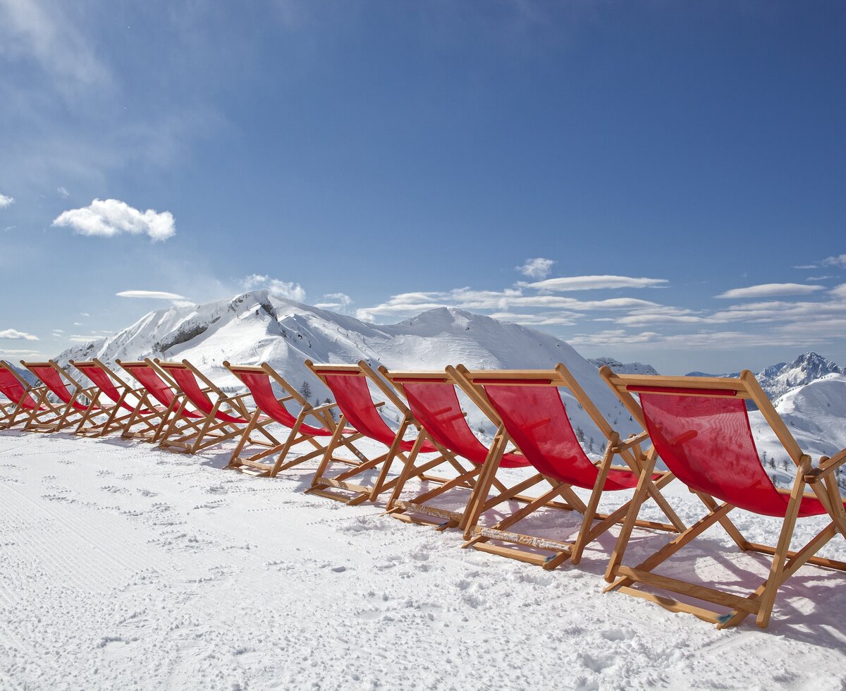 Wintersonne am Nassfeld | © Martin Steinthaler - Kärnten Werbung GmbH Liegestühle aufgereiht in der Sonne im Hintergrund das Skigebiet Nassfeld | © Martin Steinthaler - Kärnten Werbung GmbH