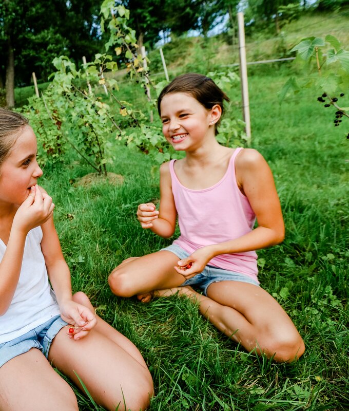 Zwei Mädchen sitzen im Gras und naschen Ribiesel | © Niederösterreich Werbung / schwarz-koenig.at