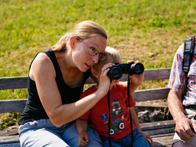 Schau, dort drüben siehst du ein Reh! | © Urlaub am Bauernhof Oberösterreich / Daniel Gollner Mama zeigt dem Bub etwas durch das Fernglas | © Urlaub am Bauernhof Oberösterreich / Daniel Gollner