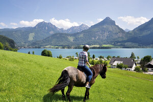 Frau reitet mit Blick auf den Wolfgangsee, Salzkammergut | © Urlaub am Bauernhof Oberösterreich / Harald Puchegger