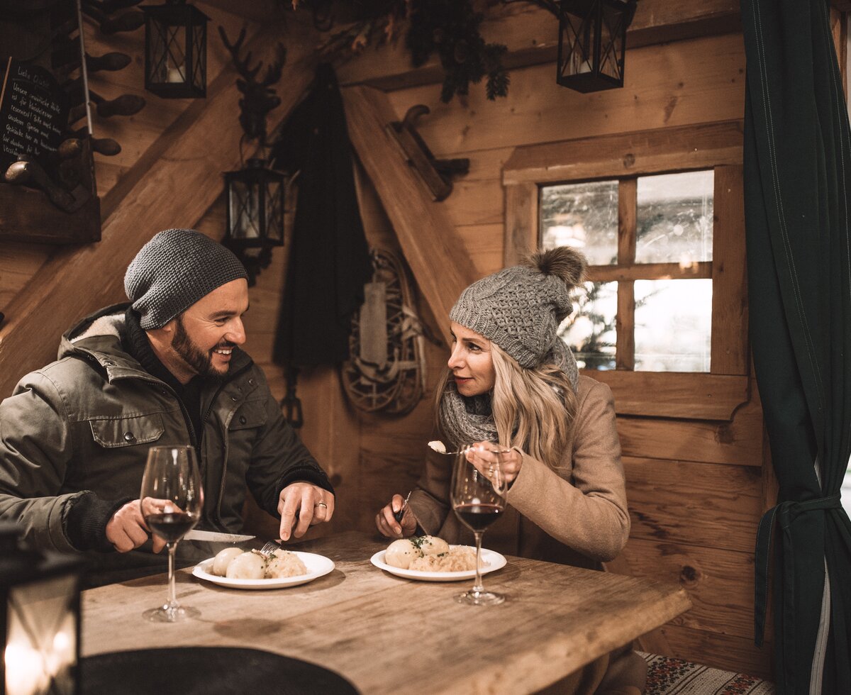 Paar sitzt in Hütte und genießt traditionelle Kulinarik am Adventmarkt in St. Wolfgang im Salzkammergut | © Oberösterreich Tourismus GmbH / Robert Maybach