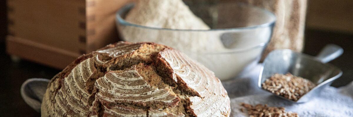 Ein Laib frisch gebackenes Brot, eine Getreidemühle und Getreidekörner | © Urlaub am Bauernhof Oberösterreich / Puremotions Photography