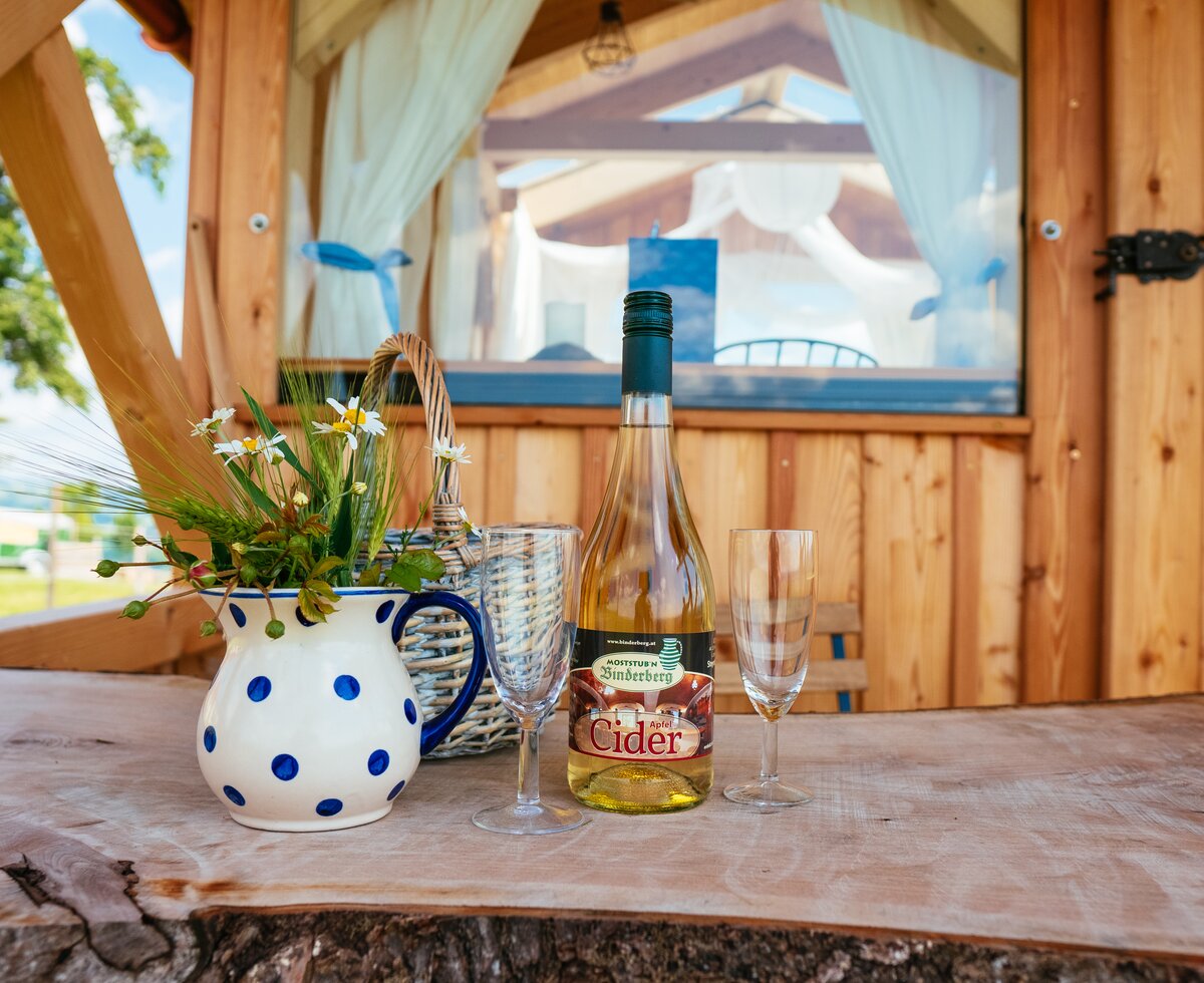 Eine Flasche Cider, ein bunt bemalter Krug und zwei Gläser stehen auf dem Tisch | © Urlaub am Bauernhof Oberösterreich / Daniel Gollner