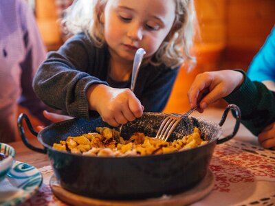 Kaiserschmarren für die ganze Familie | © Urlaub am Bauernhof Oberösterreich / Pascal Baronit Mädchen isst aus einer Pfanne mit Kaiserschmarren | © Urlaub am Bauernhof Oberösterreich / Pascal Baronit