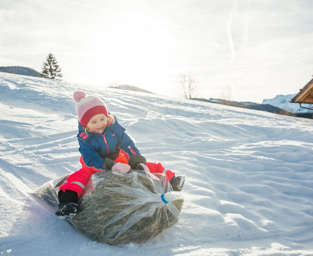 Sackrutschen im Winter | © Urlaub am Bauernhof Oberösterreich / Pascal Baronit Mädchen am Sackrutschen über den verschneiten Hang | © Urlaub am Bauernhof Oberösterreich / Pascal Baronit