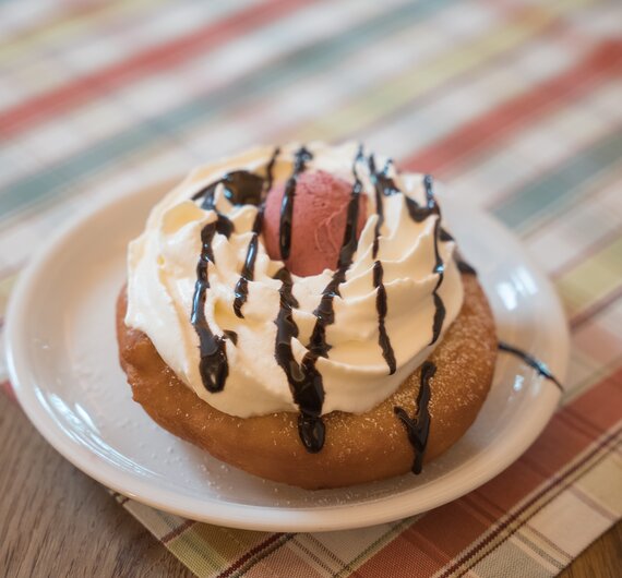 Leckerer Donut mit Sahne und Schokoladentopping auf einem gestreiften Untergrund. | © Urlaub am Bauernhof / Daniel Gollner