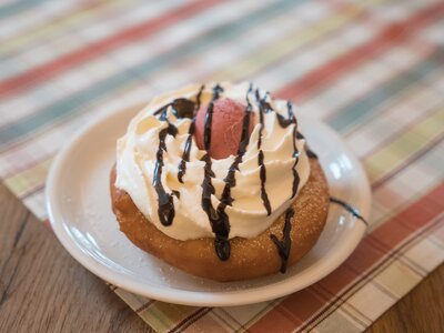 Leckerer Donut mit Sahne und Schokoladentopping auf einem gestreiften Untergrund. | © Urlaub am Bauernhof / Daniel Gollner