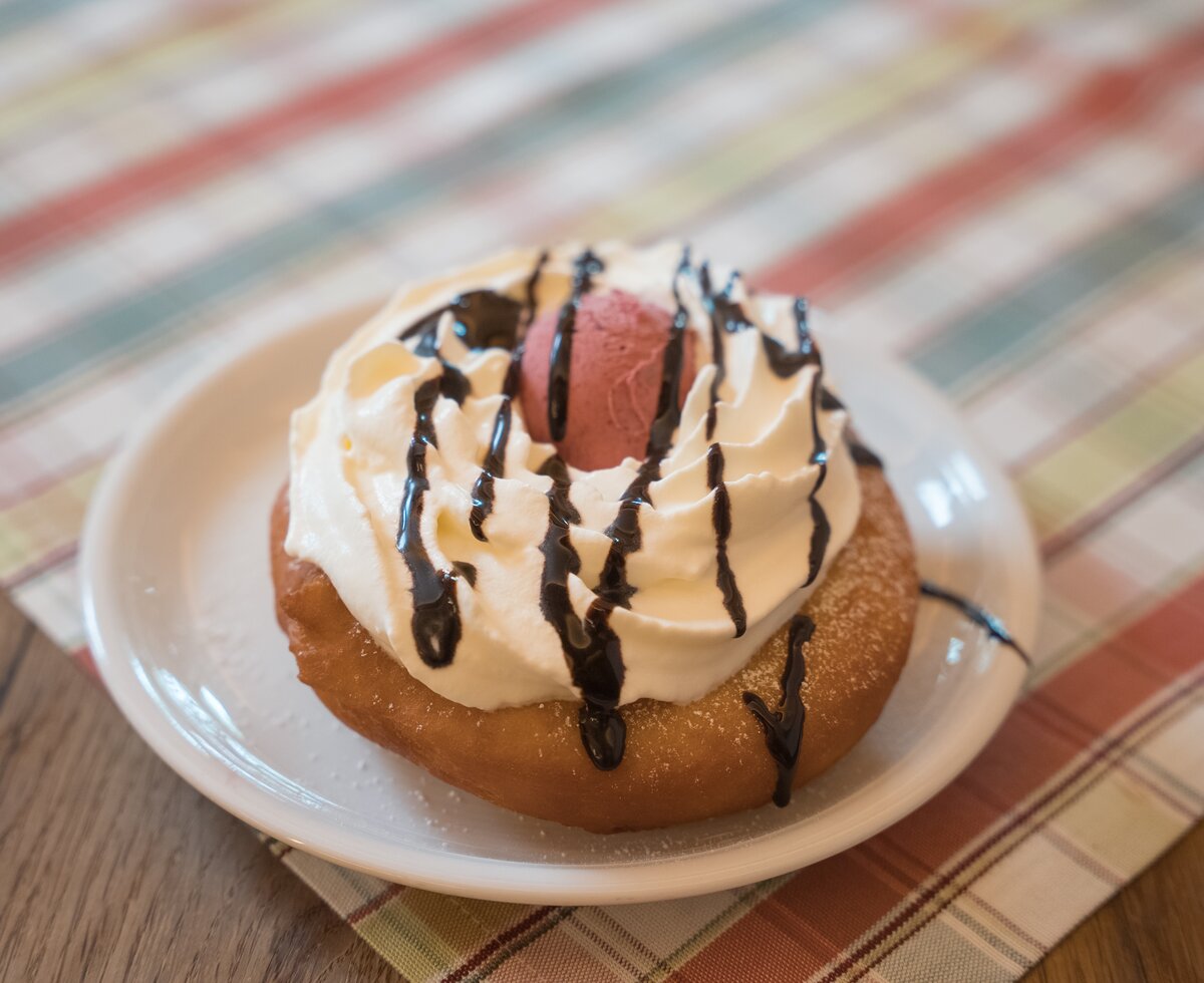 Leckerer Donut mit Sahne und Schokoladentopping auf einem gestreiften Untergrund. | © Urlaub am Bauernhof / Daniel Gollner