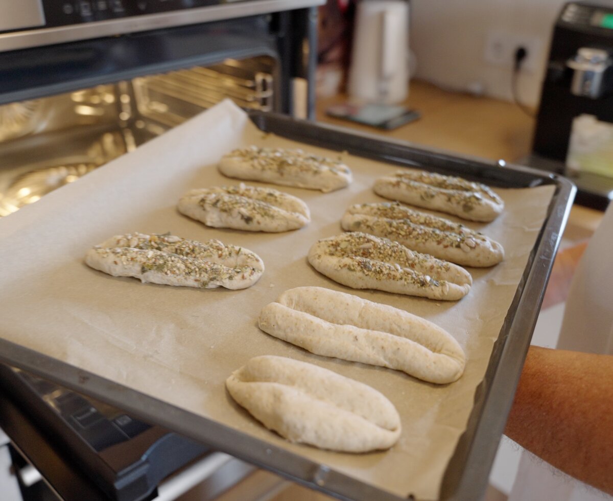 Frisch gebackene Brötchen oder Brotscheiben mit Sesamsamen auf einem Backblech in einem Backofen. | © Urlaub am Bauernhof / Daniel Gollner