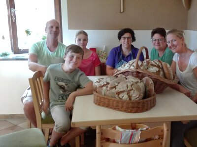 Gäste mit Brotkorb am Tisch | © Bio-Bergbauernhof Weger Gäste sitzen mit einem Brotkorb rund um den Küchentisch | © Bio-Bergbauernhof Weger