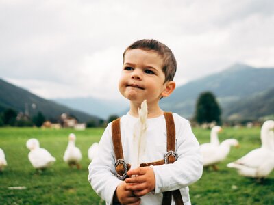 Bub mit Gänsefeder | © Urlaub am Bauernhof im SalzburgerLand / Daniel Gollner Ein Bub spielt mit einer Gänsefeder. | © Urlaub am Bauernhof im SalzburgerLand / Daniel Gollner