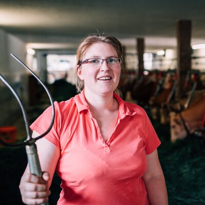 Bäuerin Maria Höpflinger steht in ihrem Stall und hat die Heugabel in der Hand. | © Urlaub am Bauernhof im SalzburgerLand / Daniel Gollner