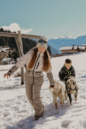 Ein Mädchen und ein Bub laufen mit Schafe. | © Urlaub am Bauernhof im SalzburgerLand/ Love_Lens_Photograph