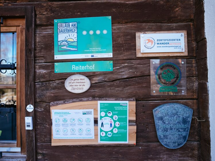 Holzwand mit Tafeln: zertifizierter Wanderbetrieb, 4 Blumen Urlaub am Bauernhof, Reiterhof, Naturparkpartner, Holztafel mit allgemeinen Informationen über das Verhalten am Bauernhof | © Urlaub am Bauernhof Steiermark / Daniel Gollner