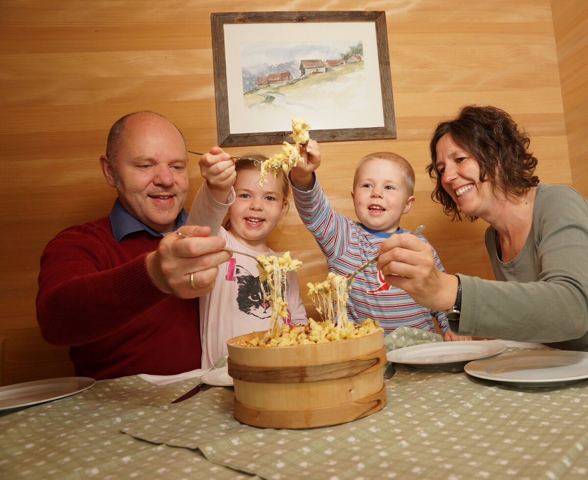 Familie beim Käsknöpfe essen am Tisch | © Urlaub am Bauernhof Vorarlberg / Ludwig Berchtold