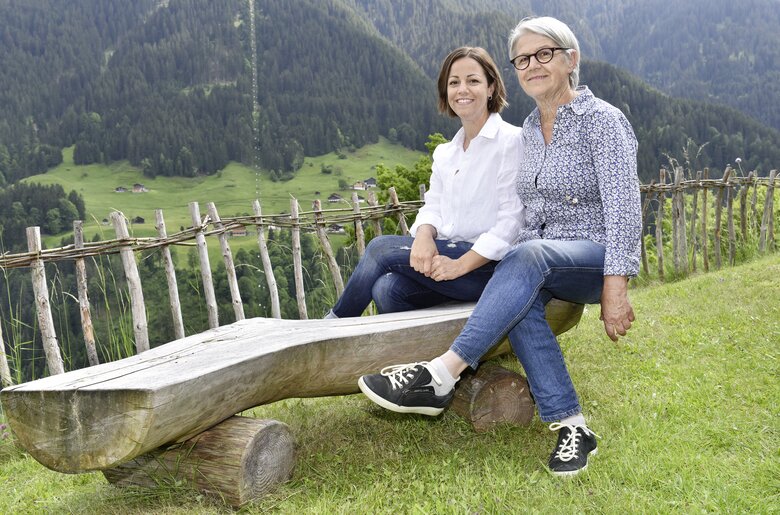 Mutter und Tochter sitzten auf einer Holzbank im Garten bei Nebelwetter | © Urlaub am Bauernhof | Andreas Künk