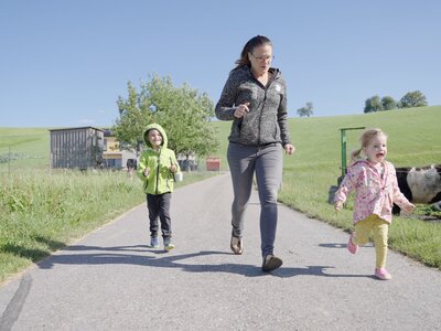 Wettrennen am Innauer Hof | © Daniel Gollner | Urlaub am Bauernhof Mutter macht mit den zwei Kindern ein Wettrennen richtung Stall | © Daniel Gollner | Urlaub am Bauernhof