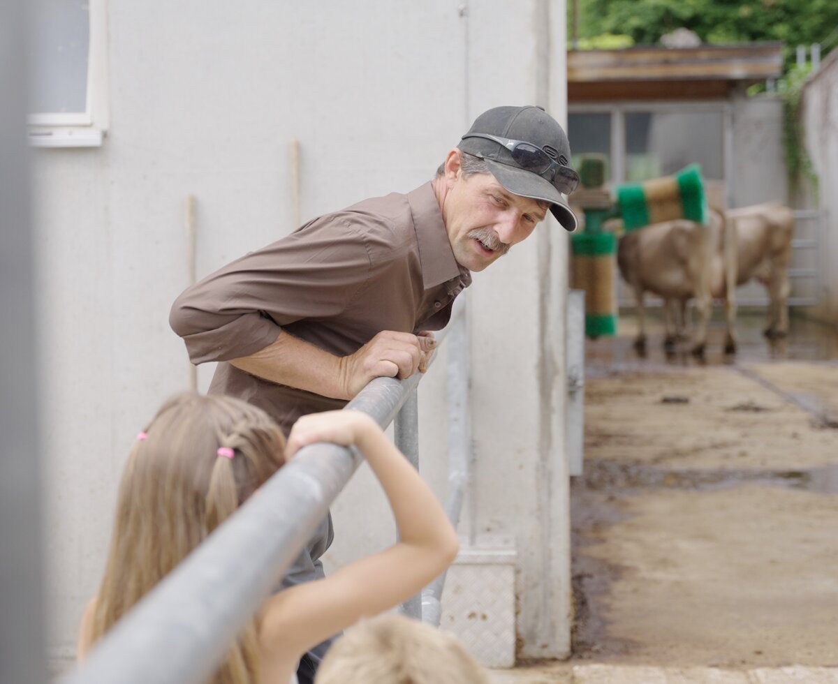 Kühe beobachten | © Urlaub am Bauernhof | Daniel Gollner Mädchen beobachtet mit dem Bauern die Kühe im Laufstall | © Urlaub am Bauernhof | Daniel Gollner