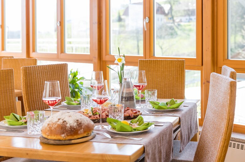 Ein gedeckter Tisch mit einer Osterjause, Frühlingsdekoration und vier Gläsern Wein. | © Urlaub am Winzerhof / ELISABETH FRÖHLICH photography