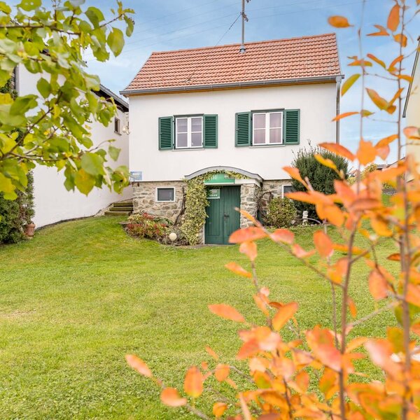 Exterior view of the Bauernhof, featuring a white building with a red tiled roof, green shutters, and a grassy lawn in the foreground.