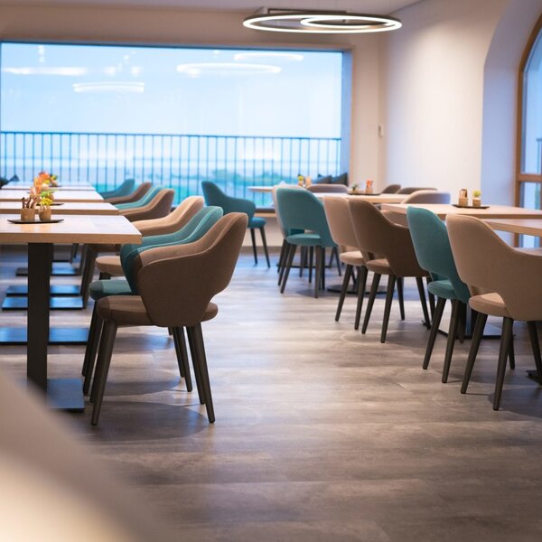 Der Aufenthaltsraum im Hof mit Tischen, Stühlen und großen Fenstern.