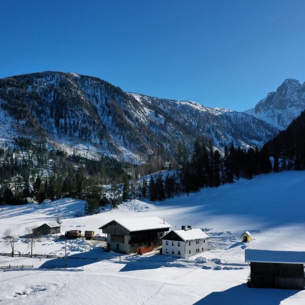 Der Bauernhof mit seinen Gebäuden in einer schneebedeckten Berglandschaft.