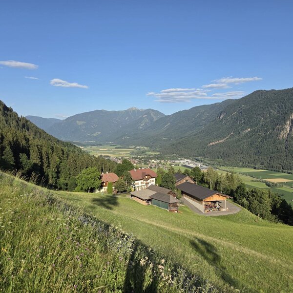 The farmhouse's idyllic location on a lush green hillside, offering sweeping views of the valley and the surrounding mountains.
