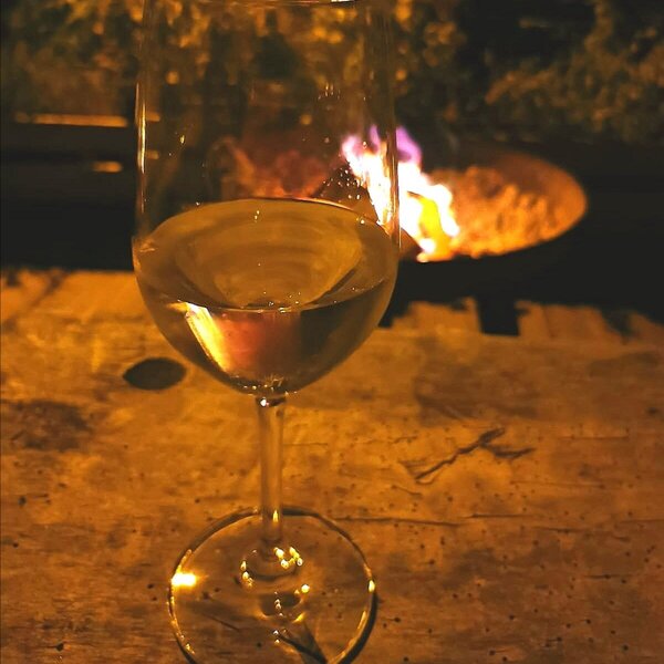 Abendlicher Ausklang auf dem Hof mit einem Glas Wein am Feuer.