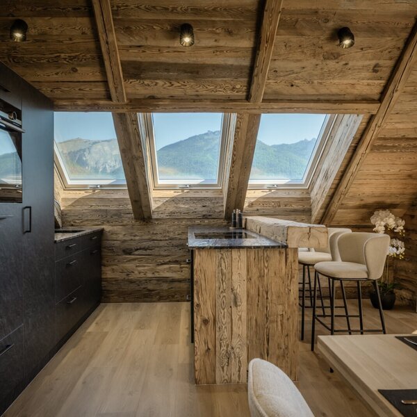 Die modern ausgestattete Küche mit Essbereich und Holzelementen im Dachgeschoss des Bauernhofs bietet Bergblick durch die Dachfenster.