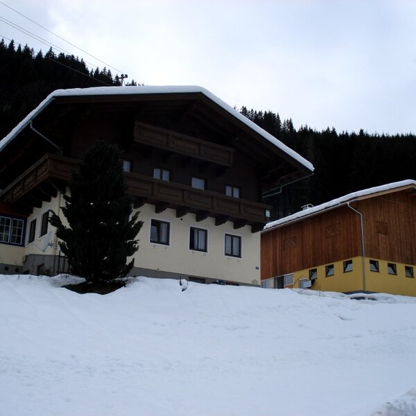Außenansicht des Bauernhofs im Winter mit Schnee, Balkonen und angrenzendem Wintergarten.
