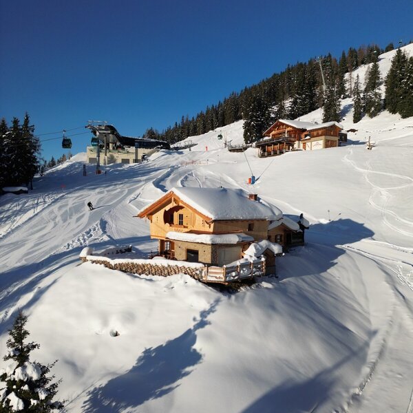 The farmhouse is situated on a snow-covered ski slope, offering direct access to skiing with a ski lift visible nearby.