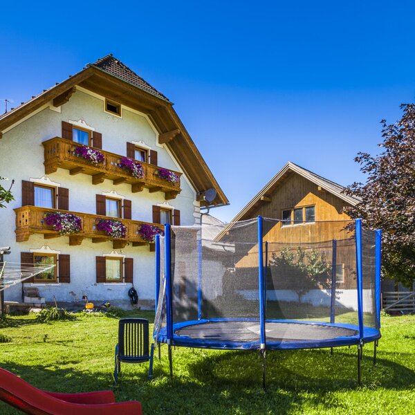 Der Außenbereich des Bauernhofs bietet eine Rasenfläche mit Trampolin und Rutsche für Kinder.