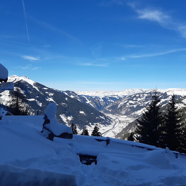 Blick auf die verschneite Berglandschaft und das Tal vom Hof.