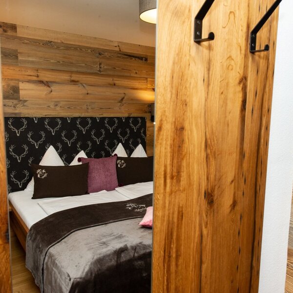 Schlafzimmer im Bauernhof mit Doppelbett, Holzwänden, SAT-TV und Garderobenhaken.